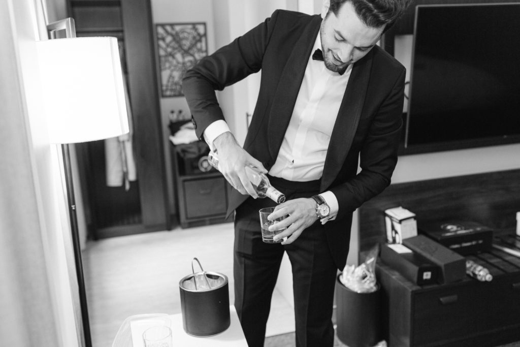 groom pouring whiskey getting ready